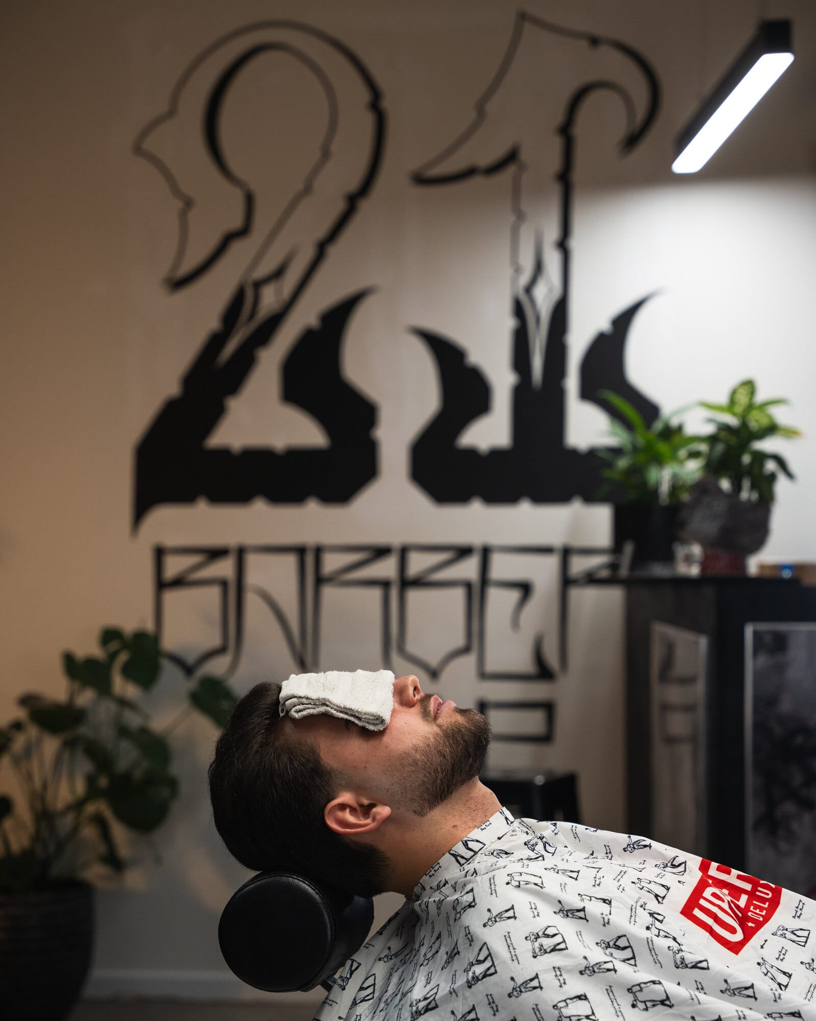 Klient w fotelu barberskim pod logo salonu